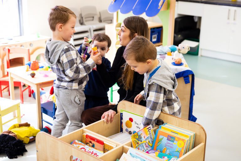A woman and three young children play in a nursery