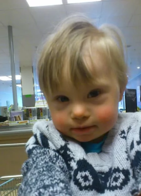 Ollie is photographed from the chest up. He is wearing a fluffy jumper. He has short blond hair.