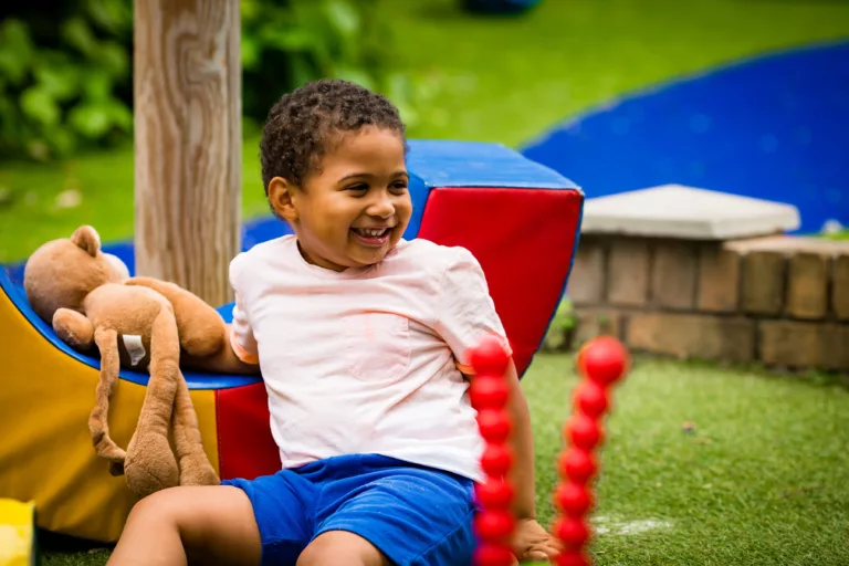 Joseph is sitting in the garden, looking at someone off camera. He is smiling.